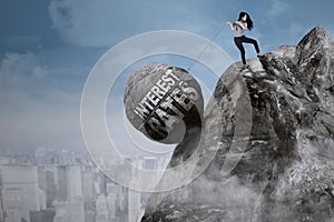 Businesswoman pulls boulder on the cliff