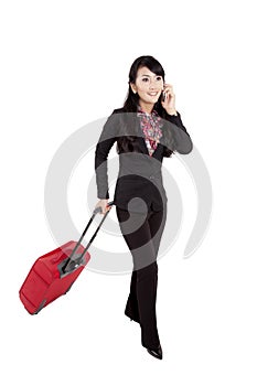 Businesswoman pulls suitcase while talking on cellphone