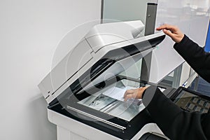 Businesswoman put documents on printer for scanning and copying in office