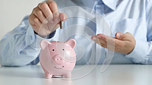 Businesswoman putting money coins saving in pink piggy bank for concept investment mutual fund finance and business