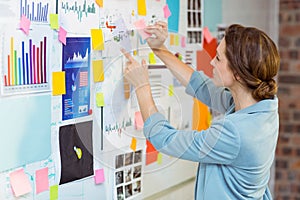 Businesswoman putting sticky notes on whiteboard