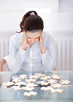 Businesswoman With Puzzle At Desk