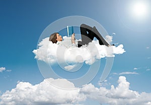 Businesswoman reading a book in a cloud