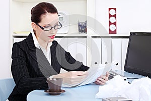 Businesswoman reading files near crumpled files
