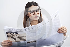 Businesswoman reading newspaper on gray background