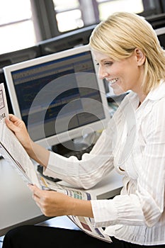 Businesswoman Reading Newspaper At Work Desk