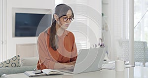 Businesswoman reading a report and writing in a notebook while checking a phone and working from home alone. One focused