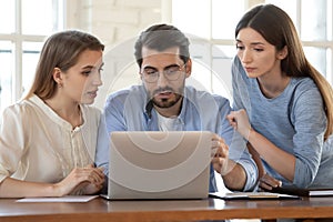 Businesswoman realtor consulting young couple at meeting, using laptop