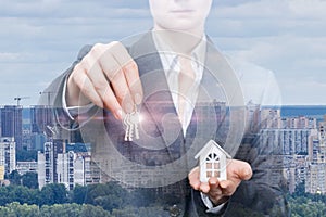 A businesswoman or realtor is holding keys and house model
