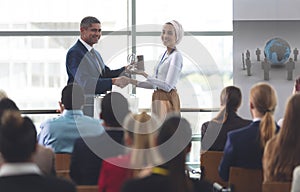 Businesswoman receiving award from businessman in a business seminar