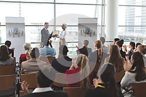 Businesswoman receiving award from businessman in a business seminar