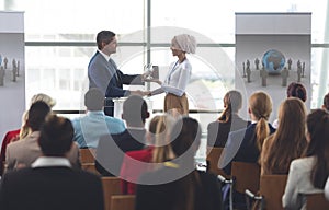 Businesswoman receiving award from businessman in a business seminar