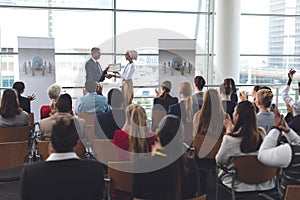 Businesswoman receiving award from businessman in a business seminar