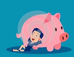 A businesswoman reclines close to the piggy bank. Saving money concept