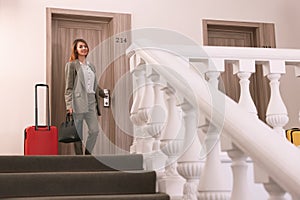 Businesswoman with red suitcase in hotel corridor