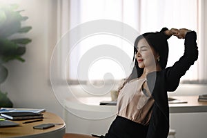Businesswoman relaxing at her workplace and stretching her arms.