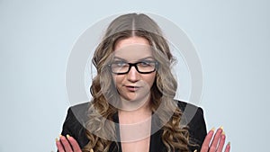 Businesswoman is reporting and tells a lot of interesting news against grey background, slow motion