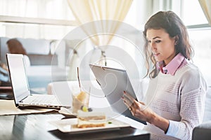 Businesswoman in a restaurant reading contract document.