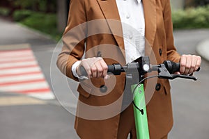 Businesswoman riding electric kick scooter on city street, closeup. Space for text