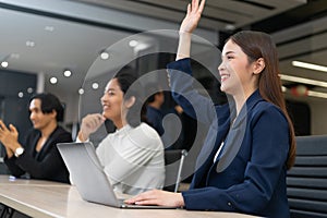 Businesswoman rises hand up for the question in the diverse employees business people team group. The colleagues discussing and