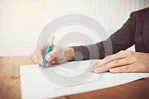 Businesswoman's hand with pen completing personal information