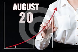 Businesswoman& x27;s hand pointing to the graph and a calendar with the date of 20 august. Business goals for the day.