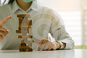 Businesswoman`s hand pointing to wooden block tower on the table, business success concept.