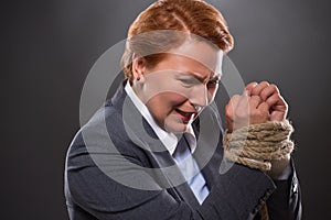 Businesswoman's hands tied up with rope