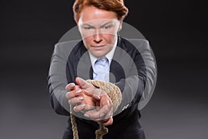 Businesswoman's hands tied up with rope