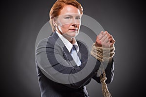 Businesswoman's hands tied up with rope