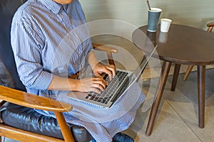 Businesswoman`s hands typing laptop keyboard at coffee table