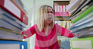 Businesswoman screaming and pulling out hair near many folders with paper documents 4k movie slow motion