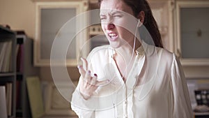 The businesswoman screams furiously while talking on the phone, wearing headphones. Angry saleswoman in the office