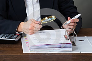 Businesswoman Scrutinizing Bills With Magnifying Glass