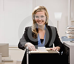 Businesswoman searches through file drawer