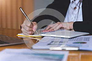 Businesswoman or Secretary holding silver pen ready to make note in opened notebook sheet. Business finances and Secretary concept