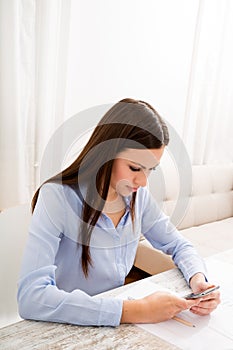 Businesswoman sending sms meanwhile working