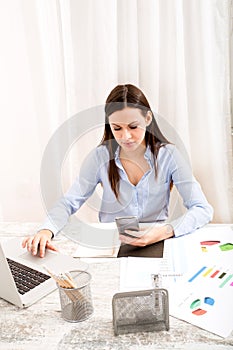 Businesswoman sending sms meanwhile working