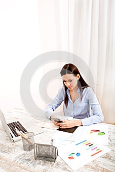 Businesswoman sending sms meanwhile working