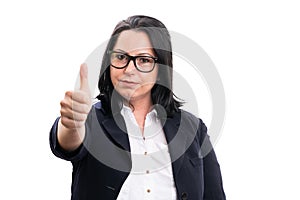 Businesswoman with serious expression making thumb up gesture