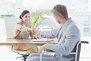 Businesswoman shaking hands with disabled colleague