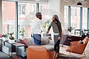 Businesswoman Shaking Hands With Male Interview Candidate In Seating Area Of Modern Office