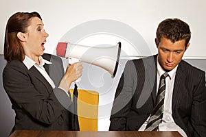 Businesswoman shouting at businessman through megaphone