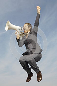 Businesswoman Shouting Into Megaphone Against Cloudy Sky