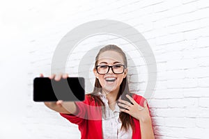 Businesswoman show cell smart phone screen with empty copy space wear red jacket glasses happy smile