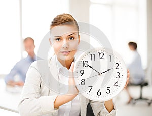 Businesswoman showing white clock in office