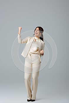 Businesswoman showing yeah gesture on grey