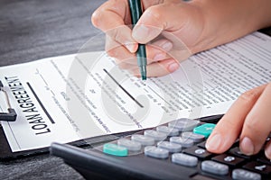 Businesswoman signed a contract loan agreement. Hand signing legal or insurance document or business contract on grey desk.