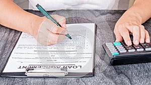 Businesswoman signed a contract loan agreement. Hand signing legal or insurance document or business contract on grey desk.