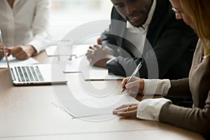 Businesswoman signing business document at diverse partners meet